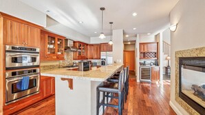A spacious kitchen with wooden cabinets, stainless steel appliances, and a large island with bar stools.