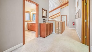 A hallway with wooden doors, a kitchen with wooden cabinets, and a ceiling with wooden beams.