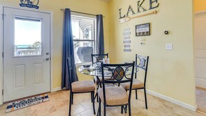 A dining area with a glass table and chairs, a door with a sign above it, and a wall with the word "LAKE" and a sign that says "Lake House".