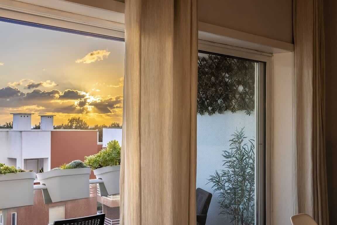 Ein Balkon mit Blick auf einen Sonnenuntergang, einer Topfpflanze und einem Stuhl.
