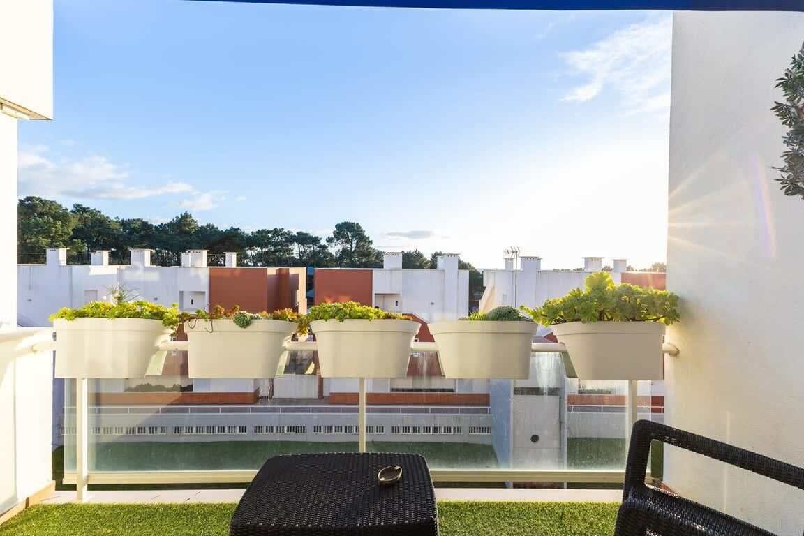 Ein Balkon mit Tisch und Stühlen, Blumentöpfen und Blick auf Gebäude.