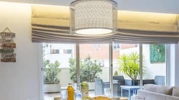 A dining area with a glass table, chairs, and a hanging light fixture.