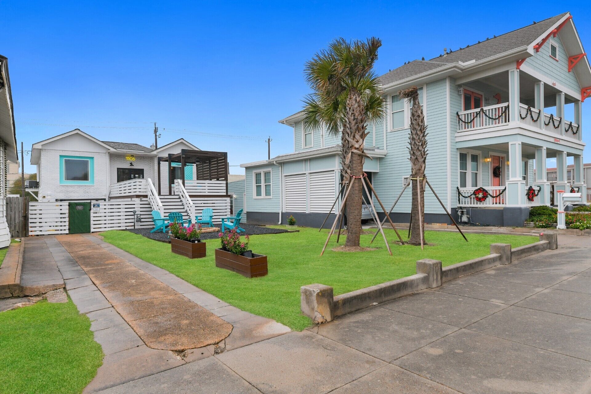 A residential area with a house featuring a porch, a small deck, and a lawn with outdoor furniture.