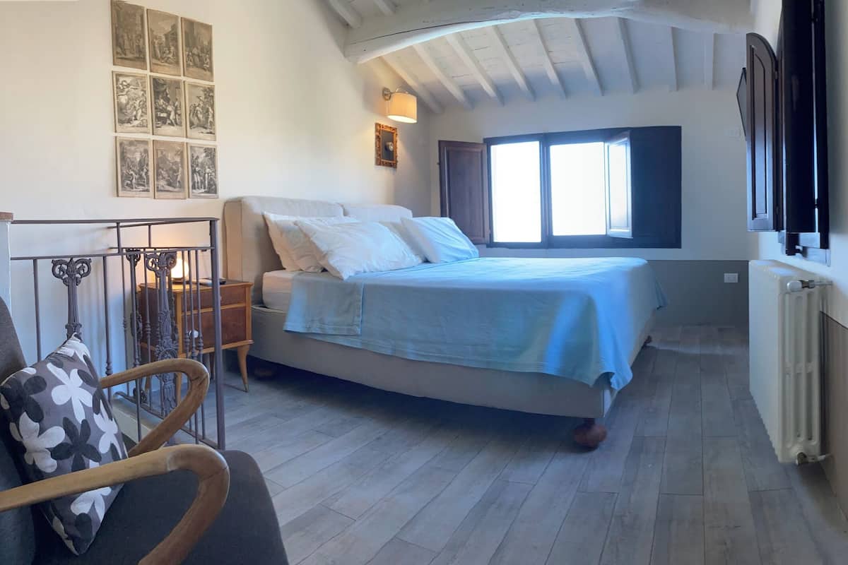 Une chambre à coucher avec un lit, une chaise, une fenêtre et un radiateur.
