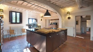 Una cocina amplia con una isla central, paredes de piedra rústica y vigas de madera a la vista.