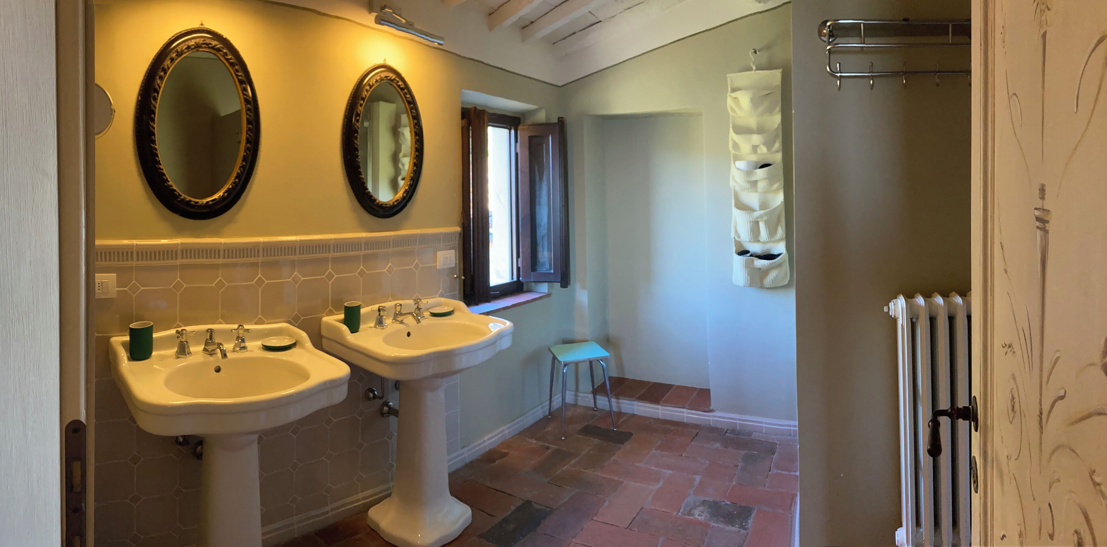 A bathroom with two sinks, a mirror, a towel rack, and a radiator.