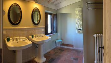 A bathroom with two sinks, a mirror, a towel rack, and a radiator.