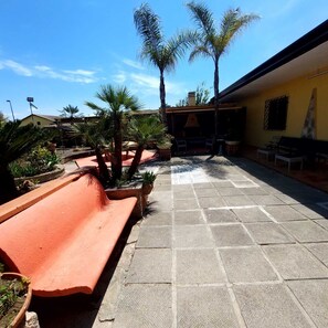 A courtyard with a tiled floor, benches, and palm trees.