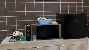 A kitchen counter with a coffee maker, microwave, and refrigerator. A blue basket with snacks is on the counter. - Within walking distance from the sea provided with all the necessary comforts (Lago)