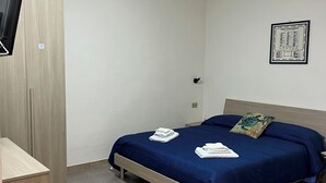 A bedroom with a bed, a desk, a chair, and a wall-mounted TV. - Within walking distance from the sea provided with all the necessary comforts (Lago)