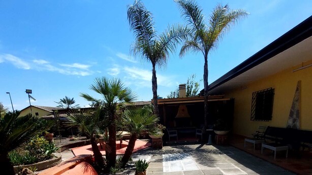 A courtyard with a tiled floor, benches, and palm trees. - Within walking distance from the sea provided with all the necessary comforts (Lago)