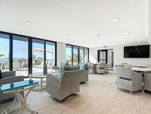 A spacious indoor area with wicker furniture, large windows, and a flat-screen TV.