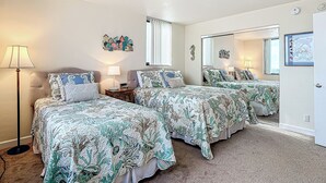 Un dormitorio con dos camas, una mesita de noche, una lámpara, un espejo y decoración en la pared.