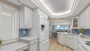 Eine moderne Küche mit weißen Schränken, einem eingebauten Kühlschrank und Blick ins Freie.