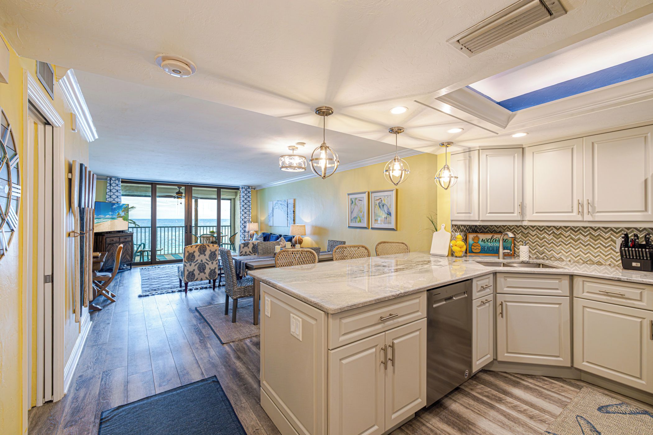 A spacious kitchen with a large island, white cabinetry, and a view to the outside.