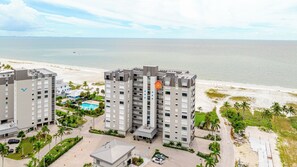 A high-rise hotel with multiple floors, a swimming pool, and a beach view.