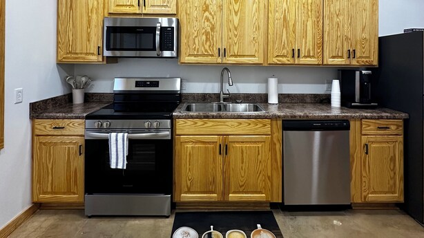 Una cocina moderna con armarios de madera, electrodomésticos de acero inoxidable y encimera negra.