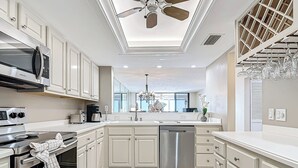 A modern kitchen with white cabinetry, stainless steel appliances, and a ceiling fan.