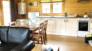 A cozy cabin-style kitchen with wooden walls, a dining area with a black leather couch, and a window with blinds. - Moor View (Oak Tree Lane)
Gorgeous rustic charm (Okehampton)