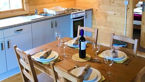A wooden interior with a dining table set for two, a window, and a kitchen area with a stove and cabinets. - Moor View (Oak Tree Lane)
Gorgeous rustic charm (Okehampton)