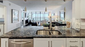 Una cocina moderna con encimera de granito, pileta de acero inoxidable e iluminación colgante.
