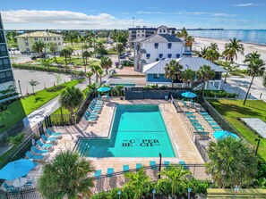 A resort with a pool area, lounge chairs, and a view of the beach and ocean.