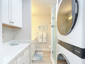 Ein modernes Badezimmer mit einer großen Waschmaschine, weißen Schränken und einem kleinen Teppich.