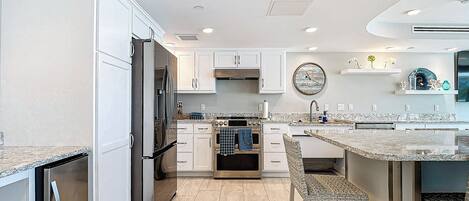 A modern kitchen with white cabinetry, a built-in oven, and a large island with seating.