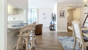 Eine moderne Küche mit Essbereich, ausgestattet mit einer großen Kochinsel, einem integrierten Spülbecken und einem an der Wand montierten Flachbildfernseher.