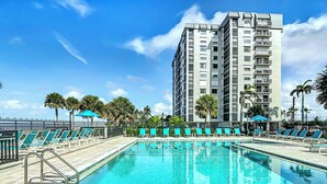A swimming pool with lounge chairs and a tall building in the background.