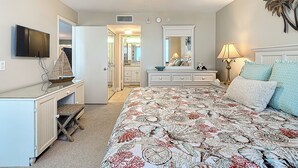 A bedroom with a bed, dresser, vanity, and a ceiling fan.