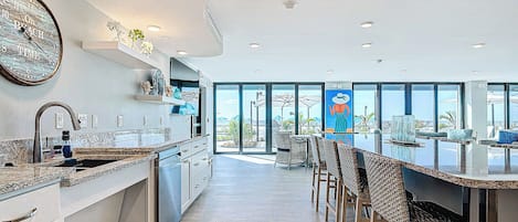 A modern kitchen with a large island, built-in appliances, and a view to the outdoors.