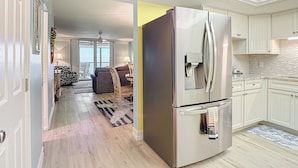 Una cocina moderna con un refrigerador de acero inoxidable, armarios blancos y un salpicadero de azulejos.
