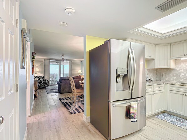 Una cocina moderna con un refrigerador de acero inoxidable, armarios blancos y un salpicadero de azulejos.