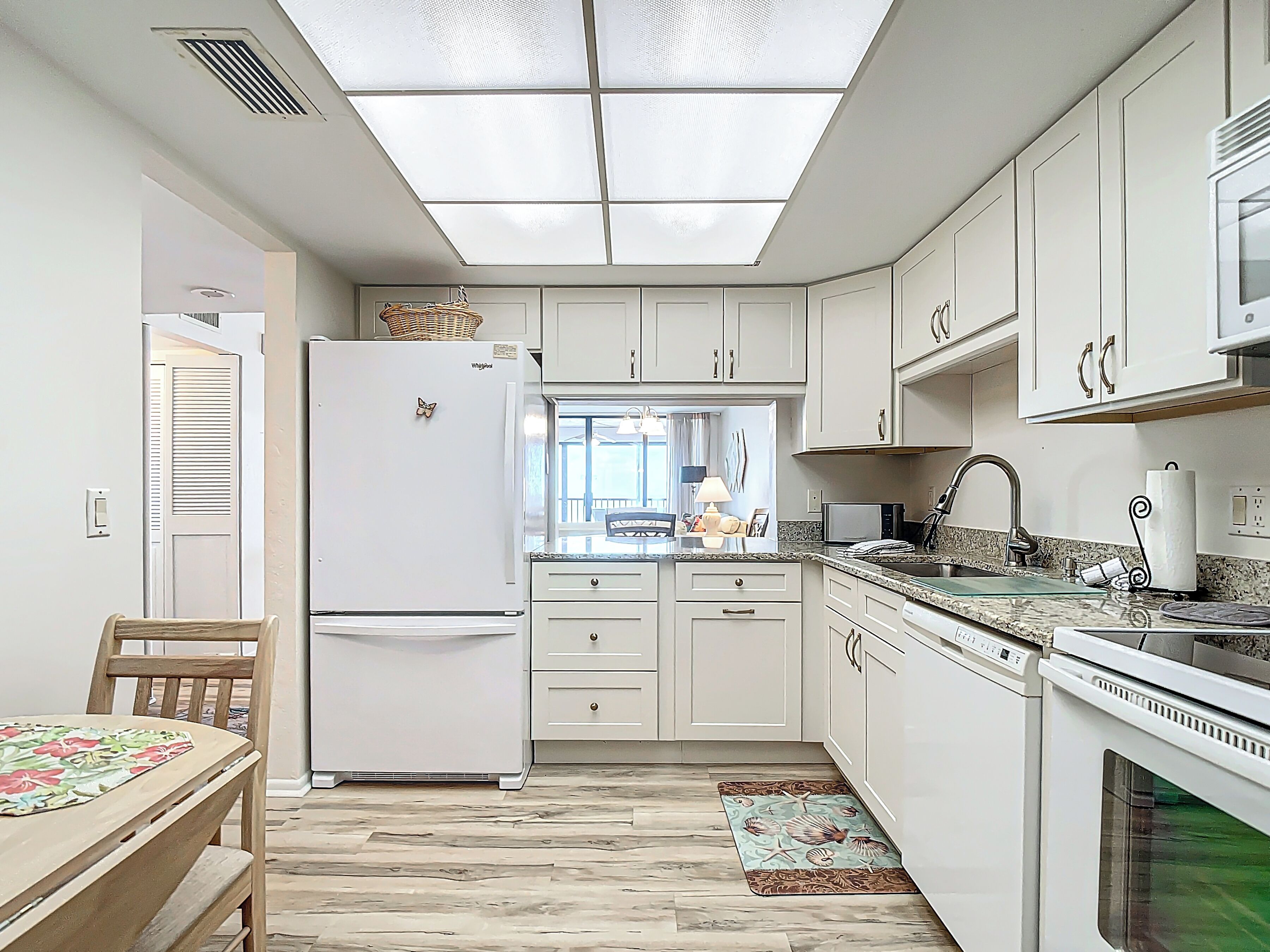 Una cocina compacta con armarios blancos, un refrigerador empotrado, microondas y lavavajillas.