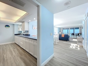 A modern kitchen with white cabinets, a black countertop, and a clock on the wall. - Beachfront Getaway at Caper Beach Club #1012 | Private Chiller/Heated Pool (Fort Myers Beach)