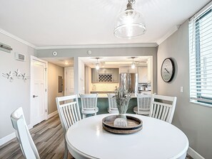 Un coin repas avec une table ronde, des chaises blanches et un lustre.