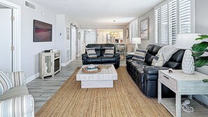 A modern living room with a sofa, armchairs, a coffee table, and a dining area in the background.