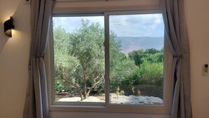 A room with a large window, grey curtains, and a wall-mounted light fixture. - Charming 2-bedroom apartment with WiFi, AC in quaint Mikhmanim (Mikhmanim)