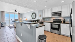 A modern kitchen with white cabinets, a central island, and stainless steel appliances.