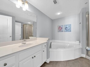 Un baño moderno con tocador doble, una bañera independiente grande y dos obras de arte colgadas en la pared.