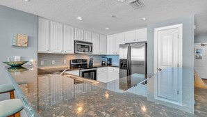 A modern kitchen with white cabinets, stainless steel appliances, and a granite countertop.