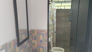 A bathroom with a tiled backsplash, a sink, a mirror, and a toilet.