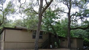 A single-story building with a wooden deck and a staircase leading to a second level. - Treehouse on the Suwannee River (Mayo)