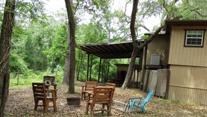 A rustic outdoor seating area with wooden benches and a picnic table, surrounded by trees and covered by a wooden structure. - Treehouse on the Suwannee River (Mayo)