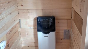 Une petite pièce fermée, aux murs en bois, avec un radiateur noir et blanc fixé au mur.