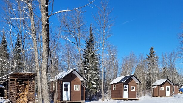 Un paysage enneigé, avec des chalets en bois et un ciel bleu dégagé.