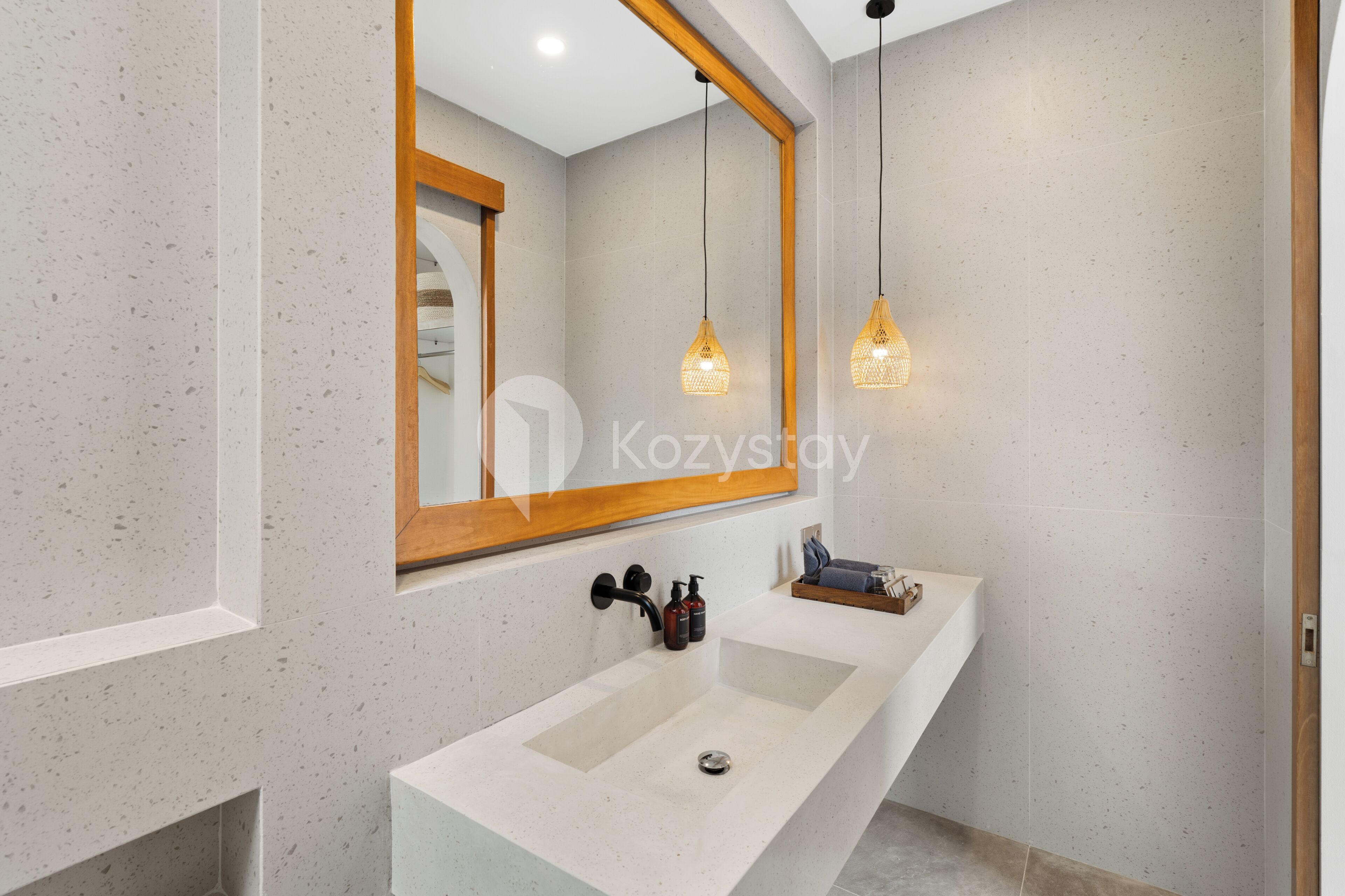 A modern bathroom with a large mirror, a white sink, and pendant lights.