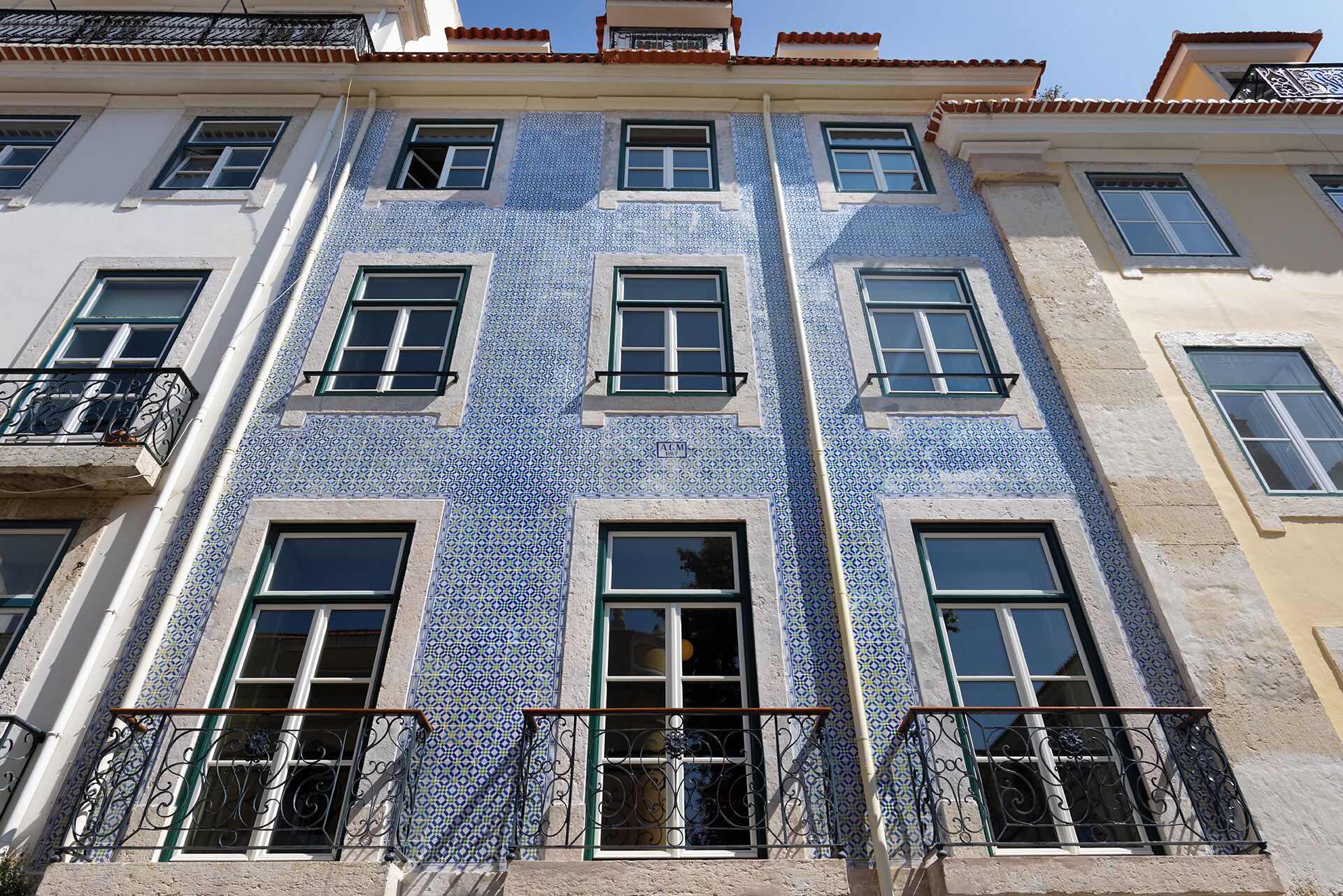 A building with blue patterned tiles, multiple windows, and balconies with wrought iron railings.