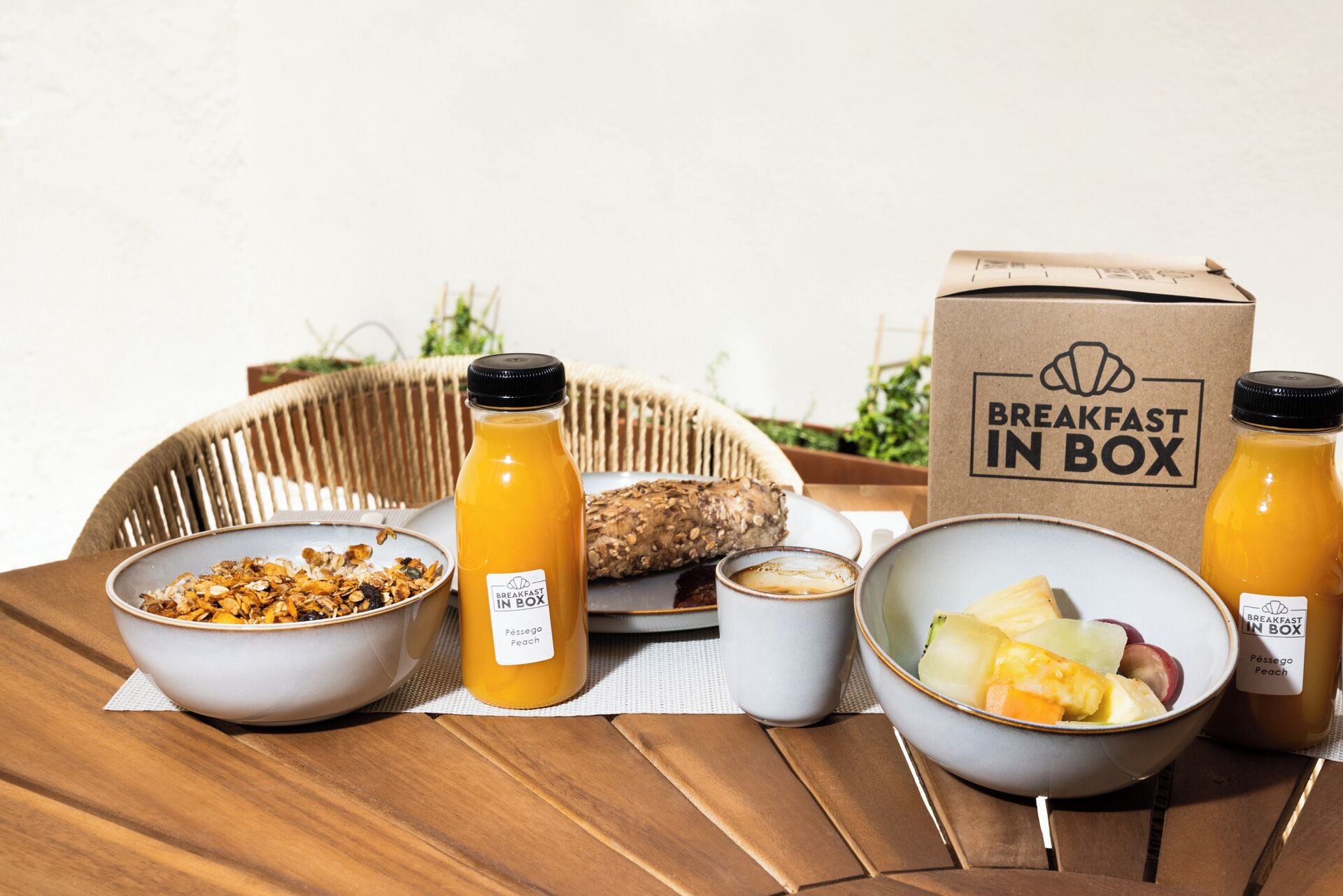 Un plateau de petit-déjeuner avec des céréales, du jus, du pain et des fruits, disposés sur une table en bois.